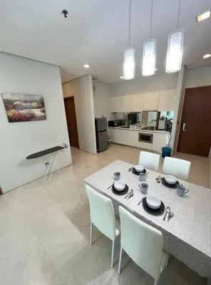 a living room with a table with chairs and a kitchen at Soho Suites, Centrally Located at KL City Centre in Kuala Lumpur