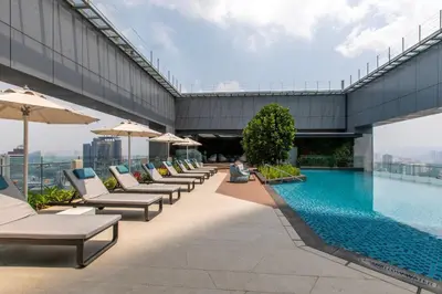 a pool on the roof of a building with chairs and umbrellas at Crowne Plaza Kuala Lumpur City Centre by IHG in Kuala Lumpur