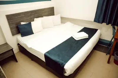 a bedroom with a large bed with white and blue pillows at V Hotel Titiwangsa in Kuala Lumpur