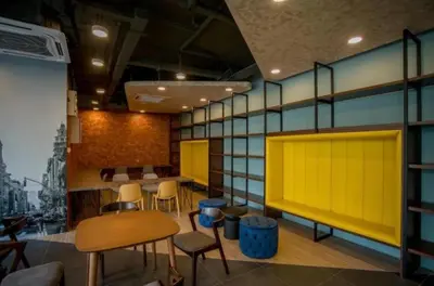 a room with chairs and tables and a yellow wall at Neu Suites by JS Home in Kuala Lumpur
