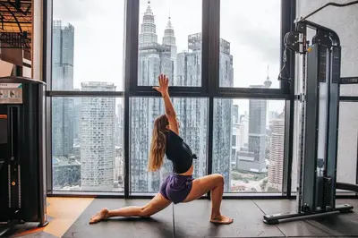 a woman doing a yoga pose in front of a window at Scarletz Suites KLCC by M Suites in Kuala Lumpur