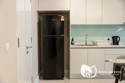 a black refrigerator in a kitchen with white cabinets at Sentral Suites by Plush in Kuala Lumpur