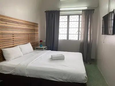 a bedroom with a large white bed with a wooden headboard at Cheras homestay @kelian in Kuala Lumpur