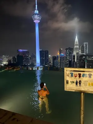 a man standing in the water in the water with a city at Ceylonz Suites Bukit Bintang by KL ONE in Kuala Lumpur