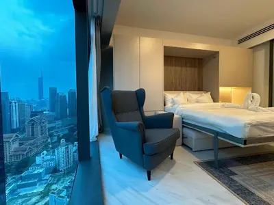 a bedroom with a bed and a chair and a window at Eaton Residences KLCC by Romeo Bnb in Kuala Lumpur
