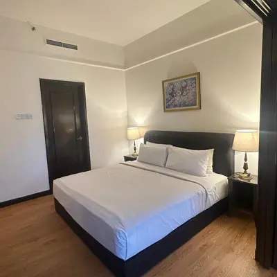 a bedroom with a bed with white sheets and two lamps at Peak Suites At Times Square in Kuala Lumpur