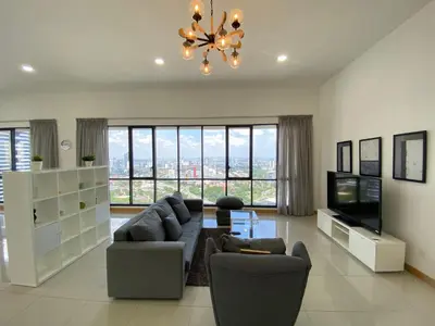a living room with a couch and a tv and a chandelier at KL Gateway Penthouse by Cobnb - 10Pax in Kuala Lumpur