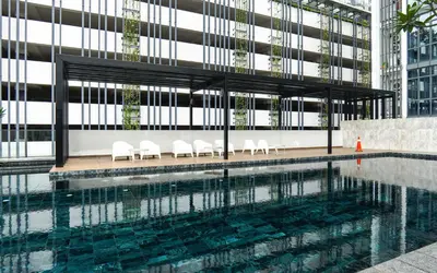 a swimming pool with white chairs and a building at VIVO at 9 Seputeh by Airhost in Kuala Lumpur