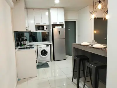 a kitchen with white appliances and a counter with stools at Mercu Summer Suites Klcc by Luxe Residence in Kuala Lumpur