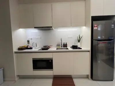 a kitchen with white cabinets and a stainless steel refrigerator at Suites TribecaTRX Kuala Lumpur by ZenGlo 5min walk to The Exchange TRX in Kuala Lumpur