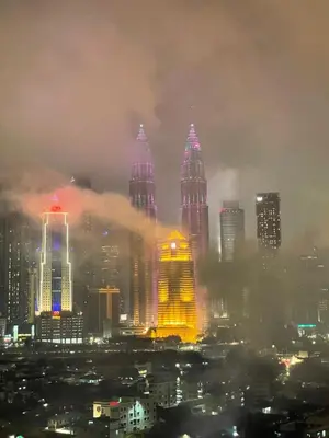 a foggy city at night with tall buildings at Nour Homestay KLCC View - COZY 2 in Kuala Lumpur