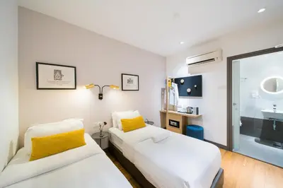 two beds in a room with a sink and a mirror at Gold3 Boutique Hotel in Kuala Lumpur