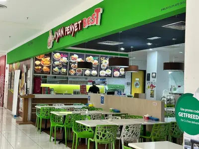 a fast food restaurant with tables and green chairs at Quill Suites KLCC in Kuala Lumpur