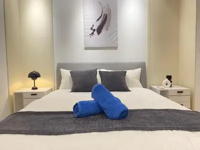 a white bed with a blue pillow on it at Eaton Suites KLCC Kuala Lumpur in Kuala Lumpur