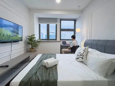 a woman is sitting at a desk in a bedroom at Riveria City KL Sentral by Sky Pool Minshuku in Kuala Lumpur
