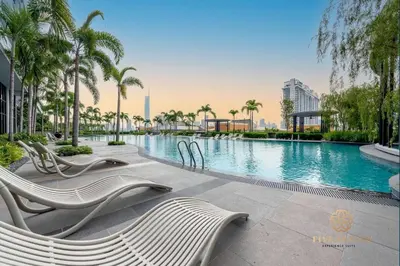 a swimming pool with chairs and palm trees at Trion Kuala Lumpur by Five Senses in Kuala Lumpur