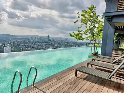 a swimming pool with benches on a wooden deck at KL Eco City Apartment by Homeizing in Kuala Lumpur