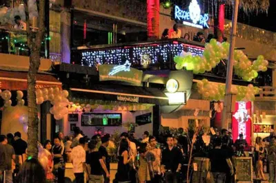 a crowd of people standing outside a bar at night at Cozy Duplex Studio near Kuala Lumpur next to LRT Train Station in Ampang