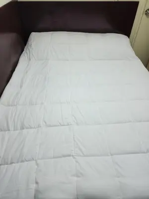 a bed with white sheets on top of it at 24Seven Guesthouse in Kuala Lumpur