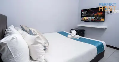 a bedroom with a bed with a tv on the wall at Neu Suites @ 3rdNvenue by Perfect Host in Kuala Lumpur