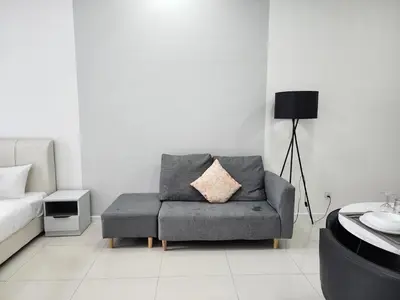 a living room with a gray couch and a pillow at Chambers Residences Suites KLCC in Kuala Lumpur
