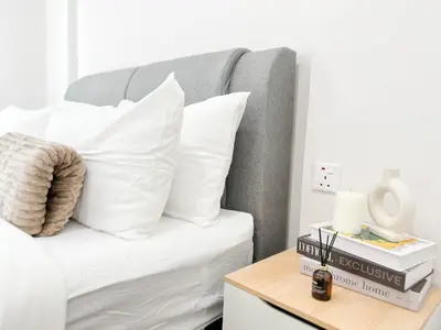a bedroom with a bed with white pillows and a table at Maison Signature Suites in Kuala Lumpur
