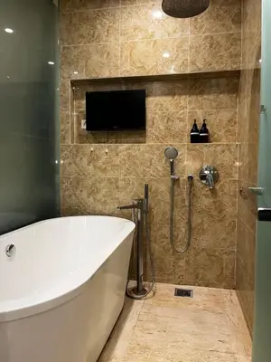 a bathroom with a tub and a tv on the wall at The Dorsett Service Suites Bukit Bintang Kuala Lumpur in Kuala Lumpur