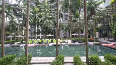 a pool with chairs and palm trees in a building at Luxurious Apartment St Mary Residences Resort Style in Kuala Lumpur