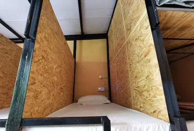 a small bed in a small room with a wooden wall at Leo Leisure Hotel @ Central Market in Kuala Lumpur