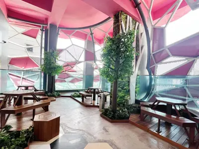 a room with tables and trees and pink ceilings at Arte plus by studio sweet home in Batu Empat