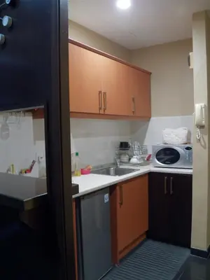 a small kitchen with wooden cabinets and a sink at Maytower Apartment in Kuala Lumpur
