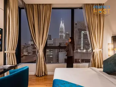 a woman standing in a hotel room looking out the window at Pavilion Ceylon Hill Suites, KLCC in Kuala Lumpur
