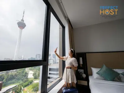 a woman standing in front of a window in a hotel room at Pavilion Ceylon Hill Suites, KLCC in Kuala Lumpur