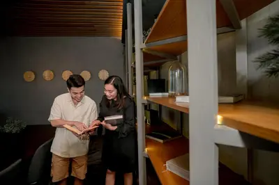 a man and woman standing in a room looking at a book at Ceylonz Suite Kuala Lumpur Bukit Bintang in Kuala Lumpur