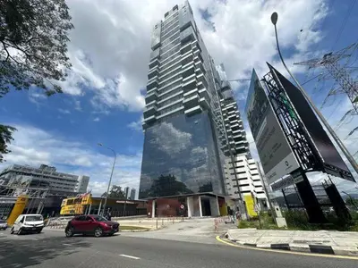 a red car driving down a street in front of a tall building at 3Towers @ KL City Centre in Kuala Lumpur