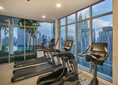 a gym with cardio machines and a large window at Royce Residence KLCC, Kuala Lumpur City Center, COBNB in Kuala Lumpur