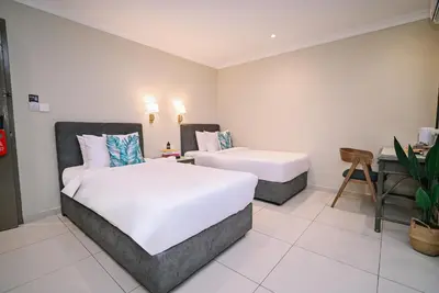 a bedroom with two beds and a table and a desk at Kingston Hotel 6 - Changkat, Bukit Bintang in Kuala Lumpur
