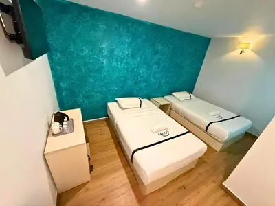 a room with two beds and a blue wall at Seeds Hotel Cheras Maluri in Kuala Lumpur