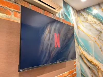 a large flat screen tv hanging on a brick wall at Seeds Hotel Cheras Maluri in Kuala Lumpur