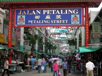 a group of people walking through a market with a sign at Oasis Guest House in Kuala Lumpur