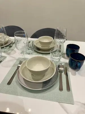 a table with plates and bowls and glasses on it at Quill Residences Suites KLCC By Dhome in Kuala Lumpur