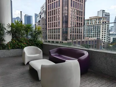 a balcony with couches and chairs and a city skyline at Quill Residences Suites KLCC By Dhome in Kuala Lumpur
