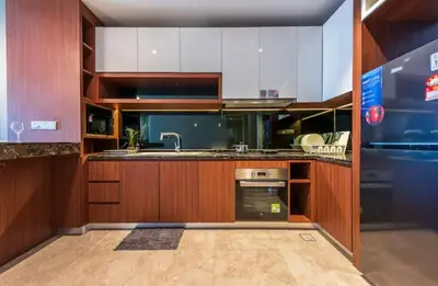 a kitchen with wooden cabinets and a sink at Anggun Residences KLCC by LuxLofts in Kuala Lumpur