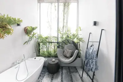 a bathroom with a tub and a chair and plants at Lloyd's Inn Kuala Lumpur in Kuala Lumpur