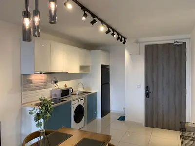 a kitchen with white cabinets and a table and a microwave at Continew by Plush Services in Kuala Lumpur