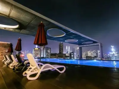 a rooftop bar with chairs and a view of the city at Cozy Suites @ D’majestic Place, KL City Centre in Kuala Lumpur