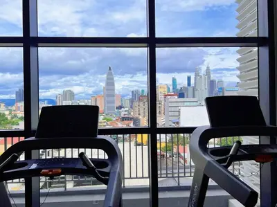 two chairs in front of a window with a view of a city at KLCC View with Balcony @ Chambers, KL Near LRT PWTC & Sunway Putra Mall in Kuala Lumpur
