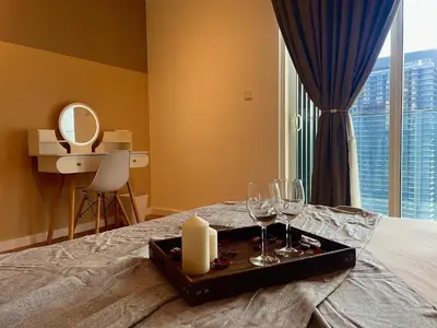 a tray with a candle and wine glasses on a bed at Quill Residences KL By Minos Home in Kuala Lumpur
