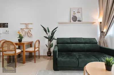 a living room with a green couch and a table at Colony Chow Kit Guesthouse in Kuala Lumpur