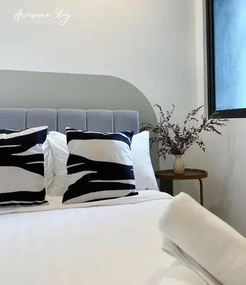 a bed with black and white pillows and a window at Neu Suites By Awesomestay in Kuala Lumpur